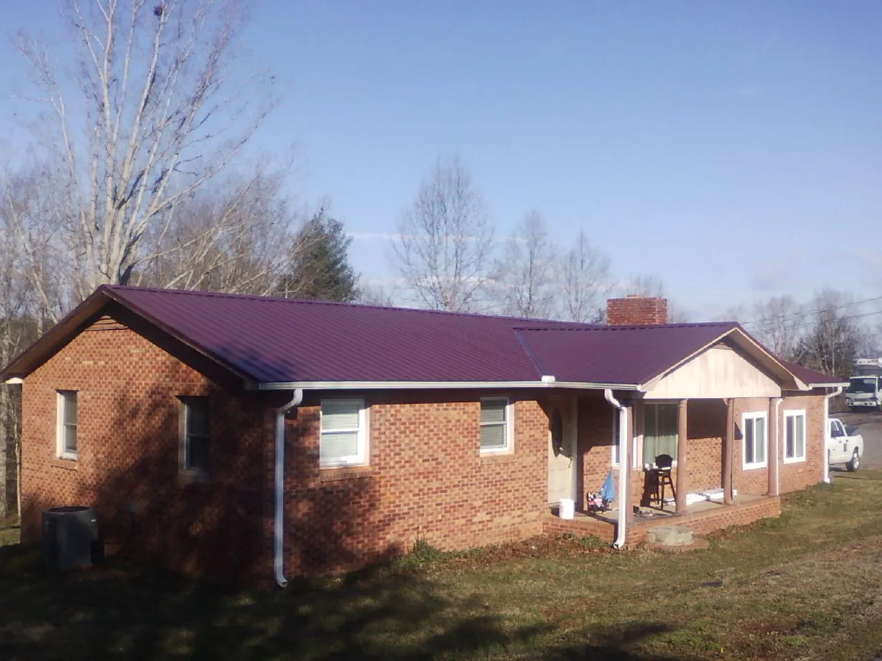 Burgundy metal roof on a brick ranch home with a new addition in Harvard